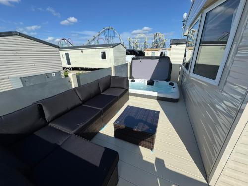 a patio with a couch and a tv on a balcony at Fantasy Island - Eastgate D7 - The Merlin with Hot Tub - Coastal Caravan Breaks in Ingoldmells