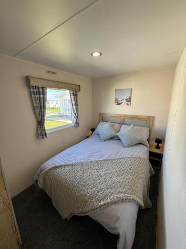 a bedroom with a bed and a window at Fantasy Island - Eastgate D7 - The Merlin with Hot Tub - Coastal Caravan Breaks in Ingoldmells