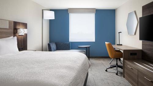 a hotel room with a bed and a desk and chair at Holiday Inn Express Dallas Market Center by IHG in Dallas