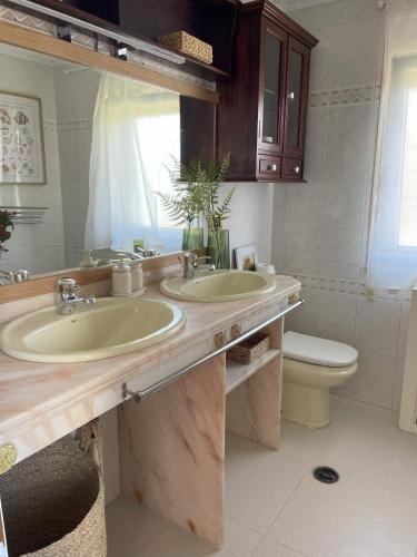 a bathroom with two sinks and a toilet at Villa Eiros in Belandres