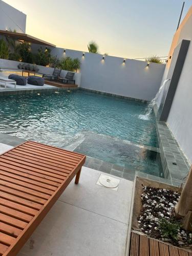 a swimming pool with a wooden bench next to a building at شاليه بيت التل Hillhouse deadsea in Al Kafrayn