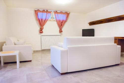 sala de estar con muebles blancos y ventana en B&B Alle Tre Rose, en Montignoso