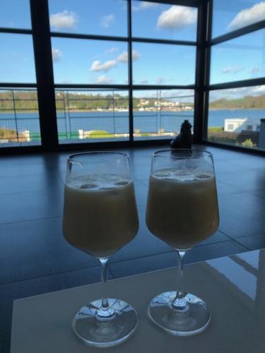 - deux verres de champagne assis sur une table avec une fenêtre dans l'établissement MAISON VILLA montmarin VUE MER BRETAGNE NORD VERS ROSCOFF CARANTEC MORLAIX PLOUESCAT LOCQUENOLE AVEC SON SPA ET SA VUE MER, à Locquénolé
