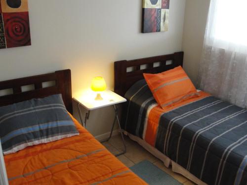 a bedroom with two beds and a night stand with a lamp at Mirador El Faro in La Serena