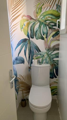 La salle de bains est pourvue de toilettes et de papier peint tropical. dans l'établissement Villa Serena - 3 chambres grand confort - 6 personnes, à Carpentras