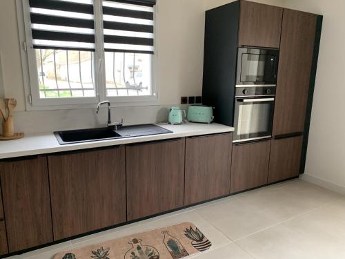 une cuisine avec des armoires en bois, un évier et une fenêtre dans l'établissement Villa Serena - 3 chambres grand confort - 6 personnes, à Carpentras
