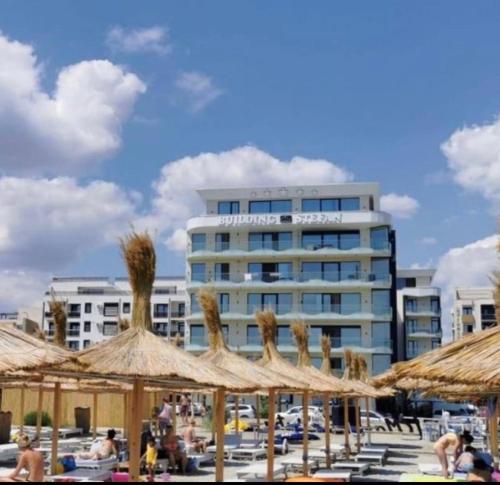 a group of straw umbrellas in front of a building at Luxury beach studio in Mamaia Nord