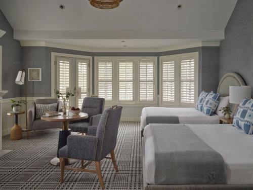 a bedroom with two beds and a table and chairs at Wequassett Resort and Golf Club in East Harwich