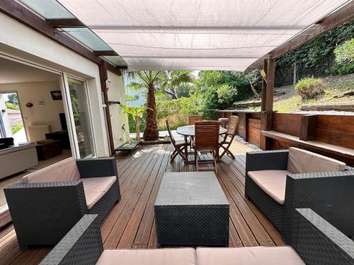 une terrasse en bois avec une table et des chaises dessus dans l'établissement Maison avec jardin et parking, à Capbreton