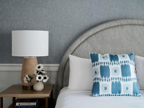 a bed with a blue and white pillow and a lamp at Wequassett Resort and Golf Club in East Harwich