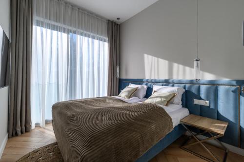 a bedroom with a bed with a blue headboard and a window at Nad zatoką Ukiel apartamenty przy jeziorze in Olsztyn