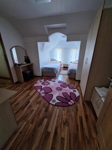 a room with two beds and a rug on a wooden floor at Pensiunea Flori in Vaţa de Jos