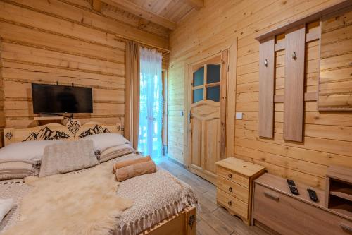 a bedroom with a bed and a flat screen tv at Apartamenty Monika SPA i Agroturystyka in Korbielów