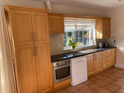 a kitchen with wooden cabinets and a white stove top oven at Bungalow in Clerihan in Clonmel
