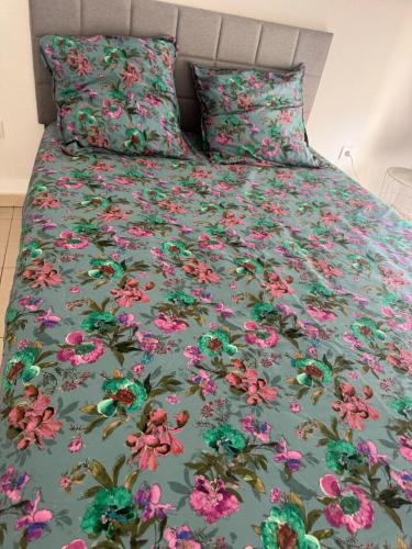 un lit avec un couvre-lit vert à fleurs roses dans l'établissement Appartement à Frejus avec piscine et terrasse, à Fréjus