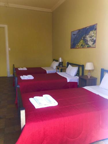 a hotel room with four beds with red sheets at Holidays Hostel Arequipa in Arequipa