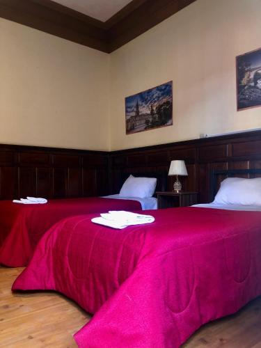 a bedroom with two beds with a red bedspread at Holidays Hostel Arequipa in Arequipa