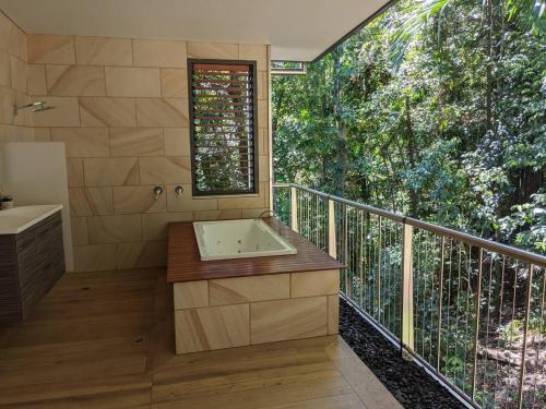 Edge HillにあるPlanchonella Rainforest Pavilionのバルコニーに浴槽と洗面台があるバスルーム