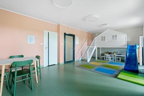 a living room with a table and chairs and a staircase at HoliApart in Nautikka Park - blisko plaży, kids club, plac zabaw, garaż podziemny in Krynica Morska