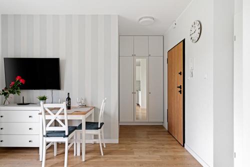 a dining room with a table and chairs and a tv at HoliApart in Nautikka Park - blisko plaży, kids club, plac zabaw, garaż podziemny in Krynica Morska