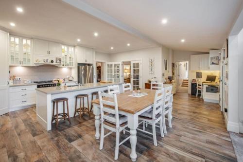 a kitchen with a wooden table and white cabinets at Botanical gardens retreat in Albury