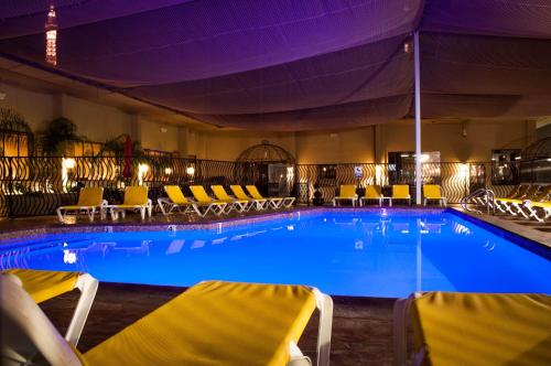 a large swimming pool with yellow chairs in a hotel at Jockey Club Suites in Las Vegas