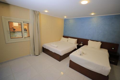 a hotel room with two beds and a window at Jewel Grand Pyramids Hotel in Cairo