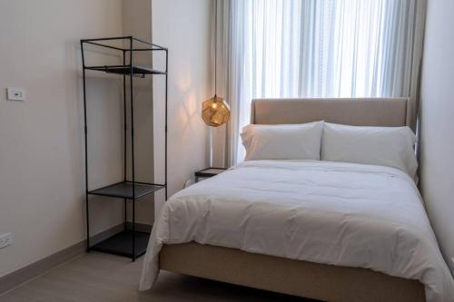 a bedroom with a white bed with a black shelf at Deluxe Condo Suite 2BR With City View in Panama City