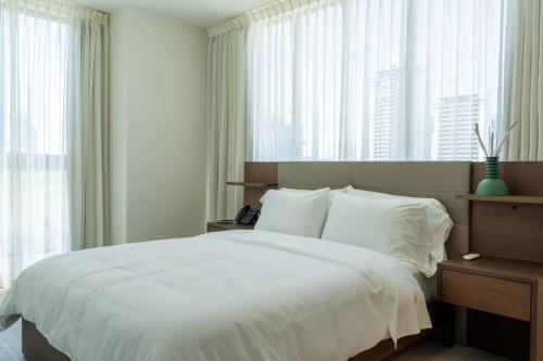 a bedroom with a bed with white sheets and windows at Deluxe Condo Suite 1BR with Ocean View in Panama City