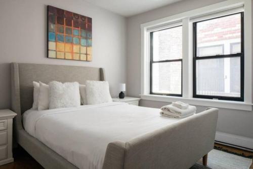a bedroom with a large white bed and two windows at Charming Theater District 1Br in Boston