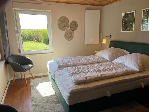 a bedroom with a bed and a window and a chair at Ferienhaus Solken mit großer Terrasse und Kaminofen in Plau am See