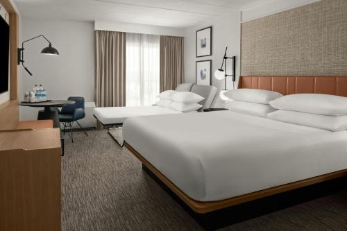 a hotel room with a large white bed and a desk at Sheraton Milwaukee Brookfield in Brookfield