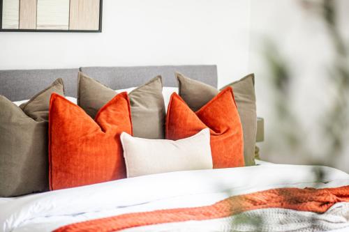 a bed with orange and gray pillows on it at The Cedar - Free Parking, Netflix, Near M1, M69 in Enderby
