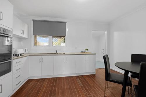 a kitchen with white cabinets and a table and a window at Rangeway Rescue - Older 3BR Home in Geraldton