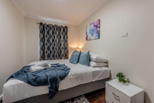 una camera da letto con un letto con cuscini blu di Rangeway Rescue - Older 3BR Home a Geraldton