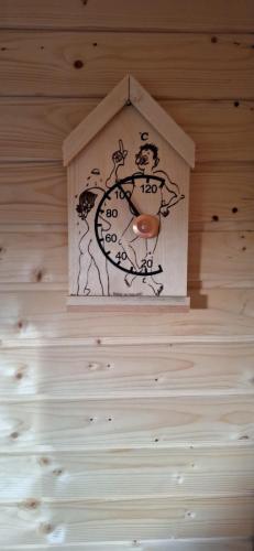 a clock on a wooden wall with a bird house at Boende Sannerud Tived in Tived