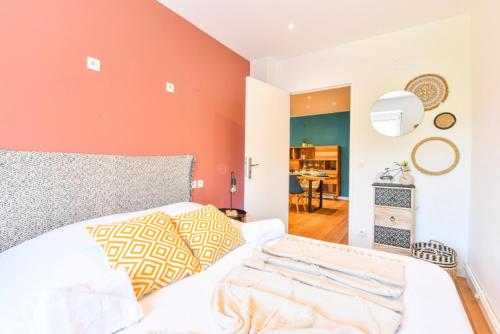 une chambre avec un lit blanc et un mur orange dans l'établissement A découvrir - L'Emergence, à Strasbourg