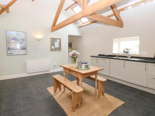 a kitchen with a wooden table and a bench at Gallow Law Cottage in Greenhaugh