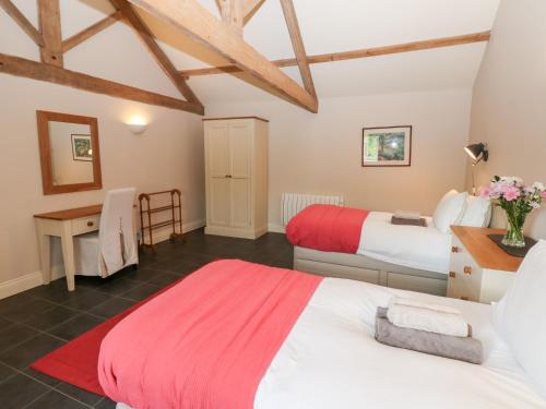 a bedroom with two beds and a desk in a room at Gallow Law Cottage in Greenhaugh