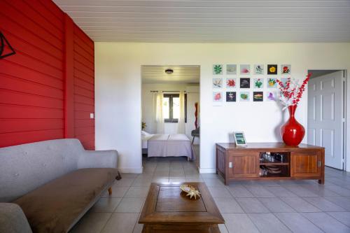 a living room with a couch and a red wall at Lodges Balourou in Montjoly