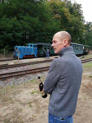 a man standing next to a train with a bottle of wine at Wochenend-Auszeit in Möckern