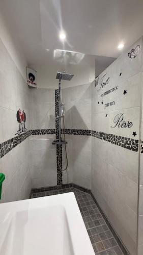 La salle de bains est pourvue d'une baignoire et d'une douche avec un mur d'écriture. dans l'établissement Résidence haut de gamme - 45m2 refait à neuf en juin 2024 avec très grande piscine chauffée, au Cap d'Agde