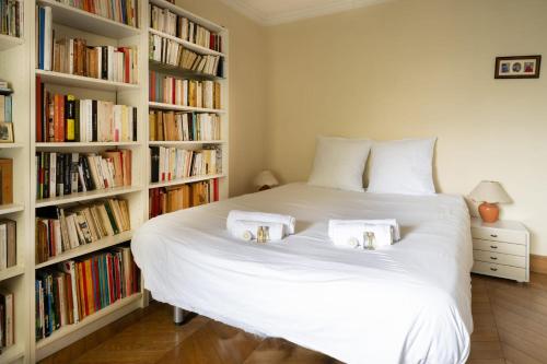 - une chambre avec un grand lit blanc et des étagères dans l'établissement Appartement de la Tour - Welkeys, à Paris