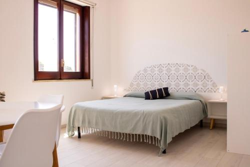 a white bedroom with a bed and a chair at Casa Baí in Torre Nubia