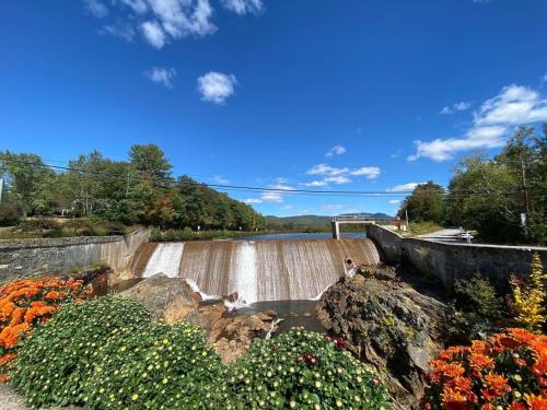 a dam with a waterfall and flowers in front of it at Campton Mountain Ski Retreat for Year-Round Fun -Best view and Best Price Guarantee in Campton