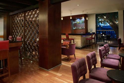 a restaurant with a bar with purple chairs at Marriott Puebla Hotel Meson del Angel in Puebla