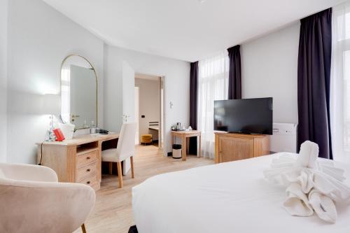 a bedroom with a white bed and a desk and a television at Best Western Plus Le Picardy in Saint-Quentin