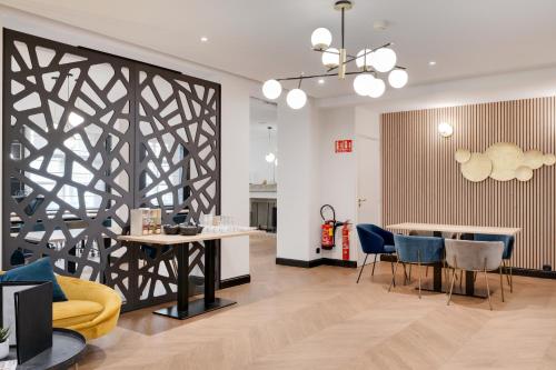 a living room with a table and blue chairs at Best Western Plus Le Picardy in Saint-Quentin