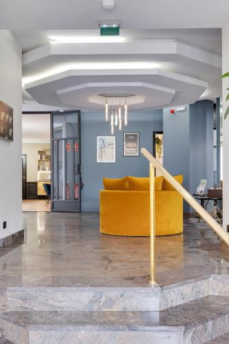a yellow couch in a room with blue walls at Best Western Plus Le Picardy in Saint-Quentin