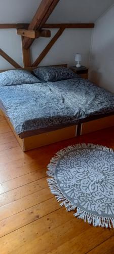 a bed in a room with a rug on a wooden floor at Prém Malom Vendégház in Bakonynána